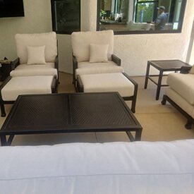Luxury ivory outdoor deep seating cushions on a dark metal frame lounge set with a dark woven coffee table and side table.