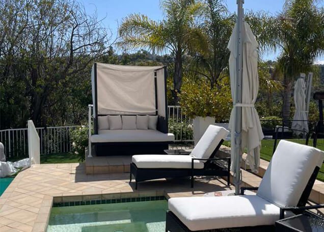 Luxury poolside patio furniture set featuring custom white cushions for lounge chairs and a covered daybed in Van Nuys, California.