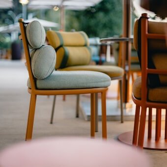 Modern outdoor chairs with sage green and mustard yellow round cushions, highlighting expert patio furniture restoration by WM Design Furniture in Van Nuys.